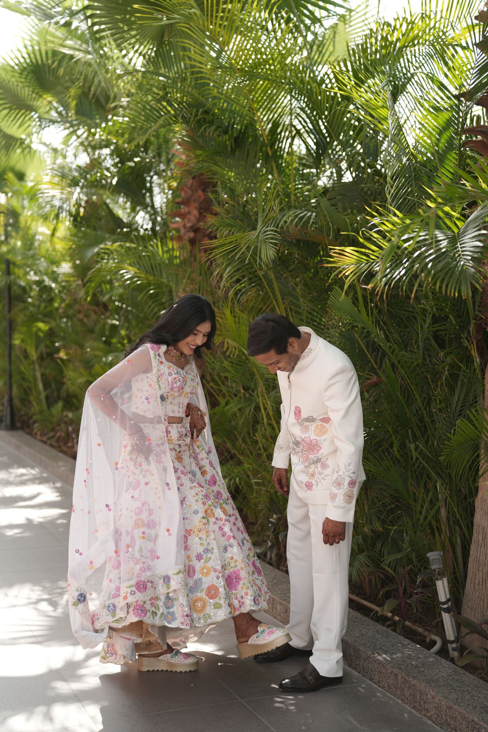 Ravi bending to straighten the hem of Saloni's lehenga
