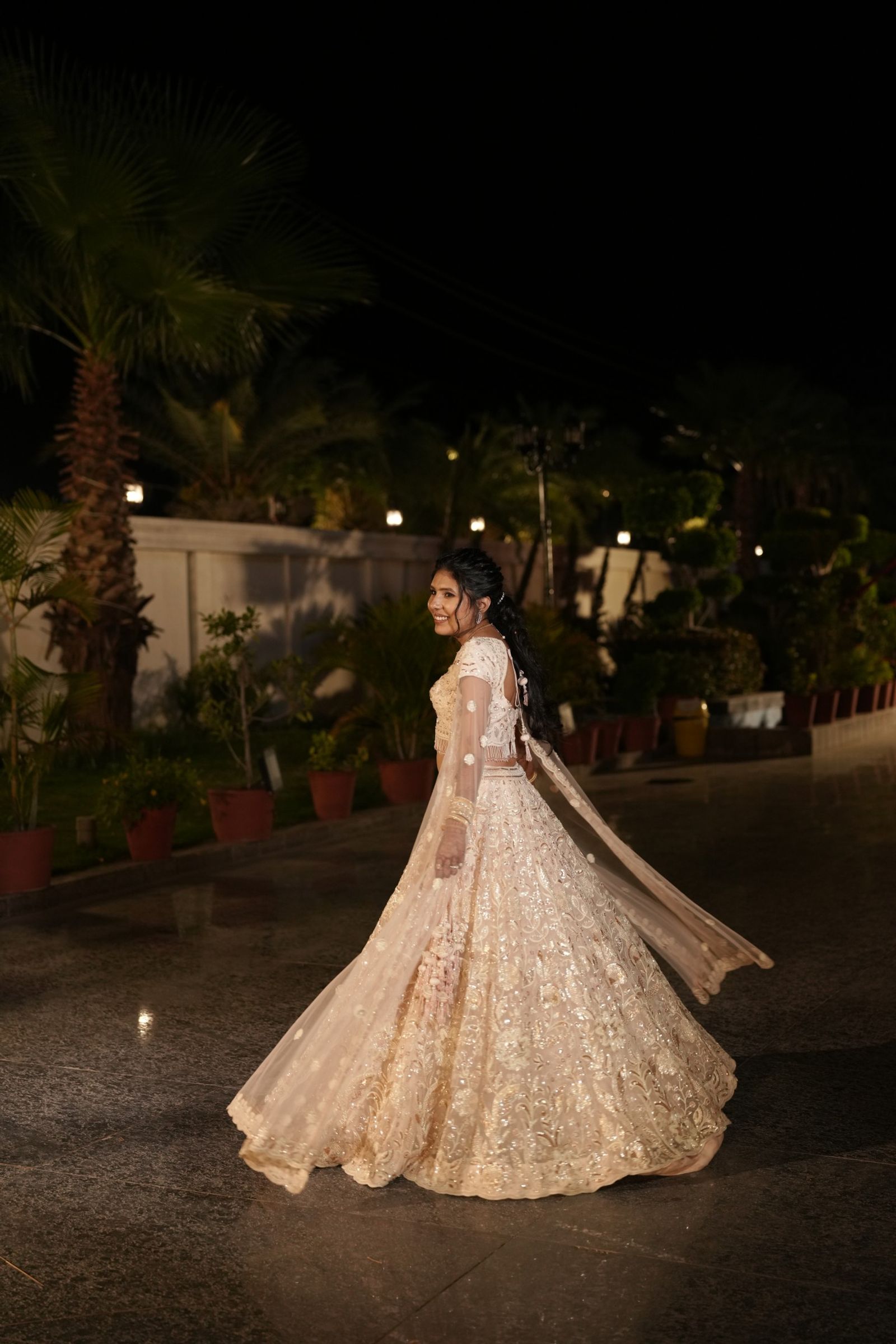 Saloni twirling in her ivory lehenga on the lawn at night