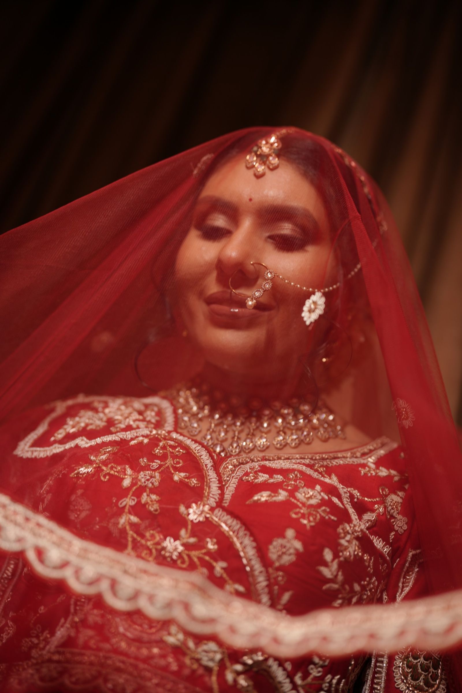 Saloni smiling under her red veil