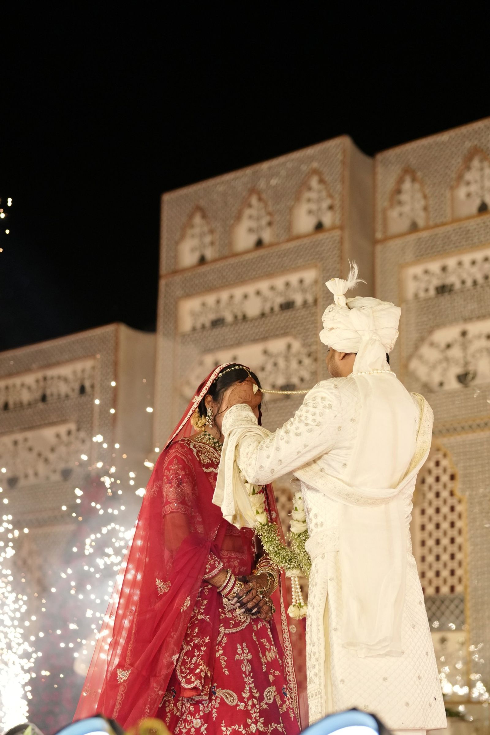 The varmala, sparklers rising behind them