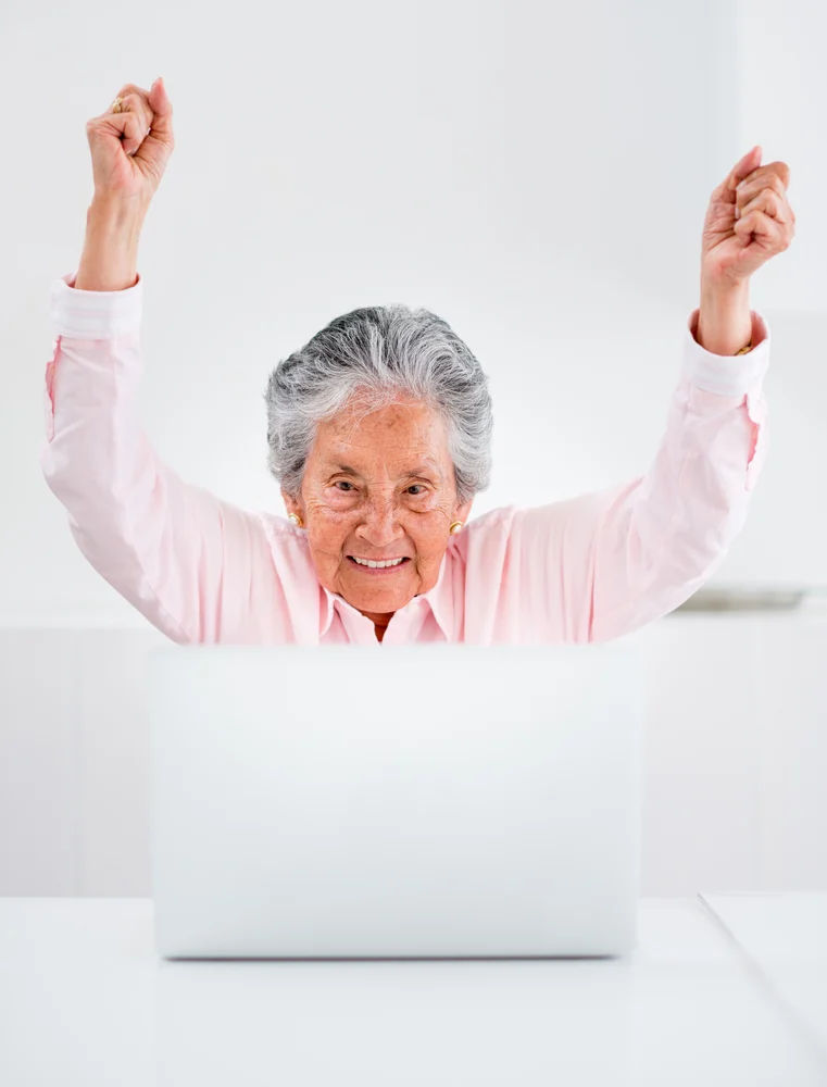 6317-happy-elder-woman-with-a-laptop-and-arms-up.webp