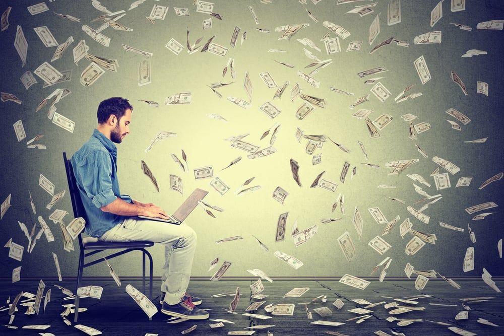 6326-young-man-using-a-laptop-building-online-business-making-dollar-bills-cash-falling-down-be.jpeg