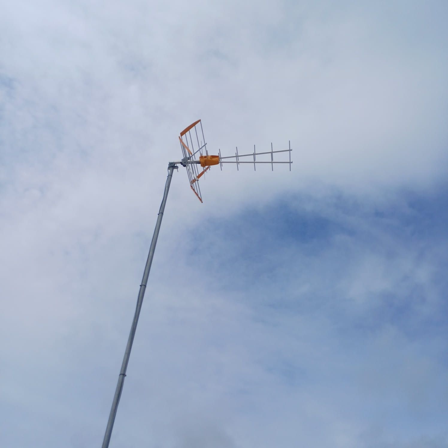 Antena de televisión terrestre instalada sobre una estructura metálica, vista contra el cielo.
