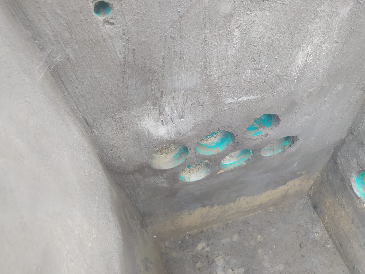 Detalle de conductos de color verde que llegan a un recinto de concreto durante la obra.