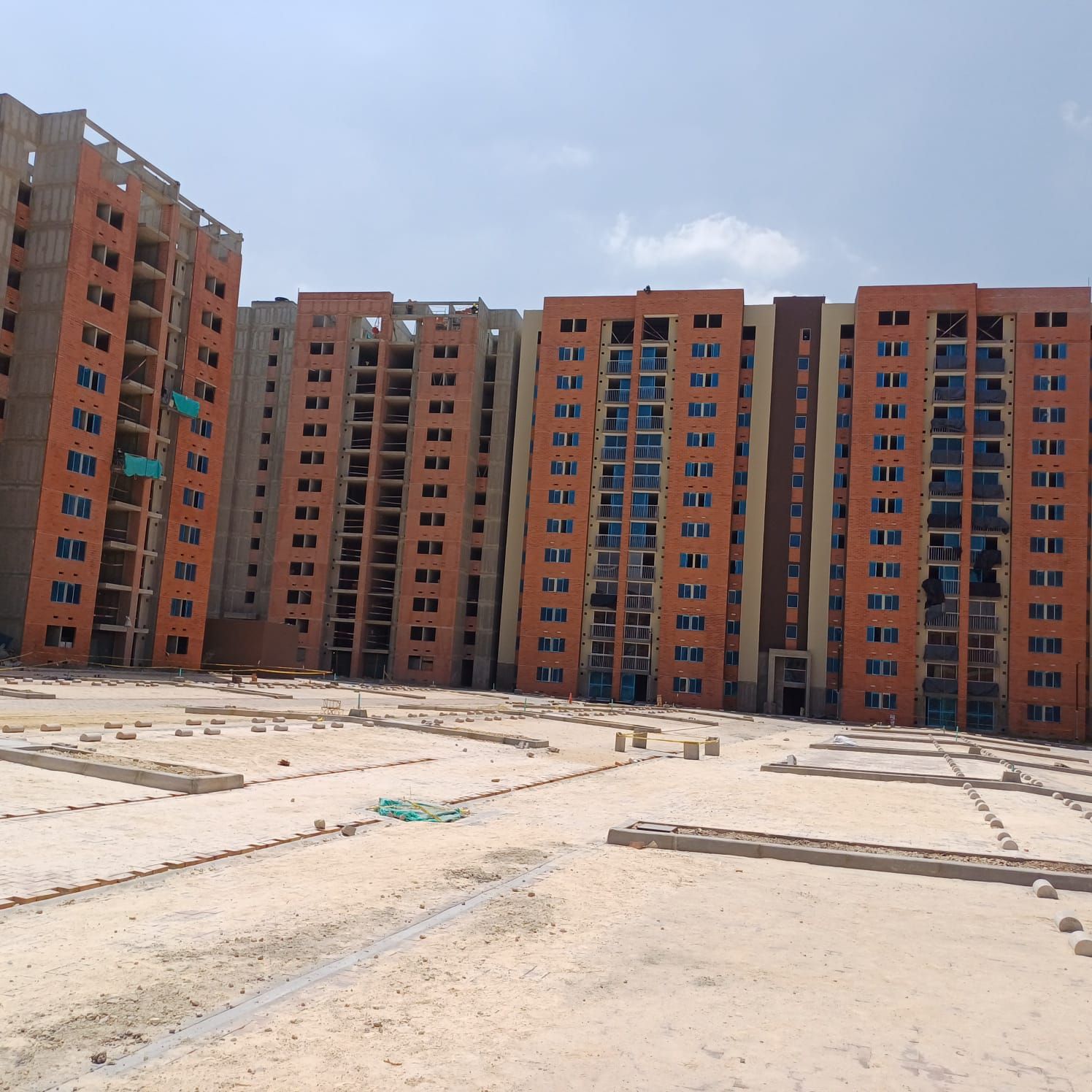Edificaciones residenciales en construcción y zona de obra en primer plano.