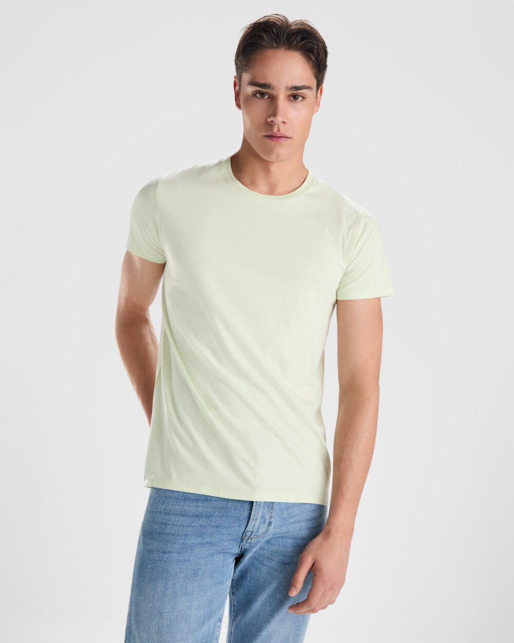Hombre joven con camiseta verde clara y vaqueros