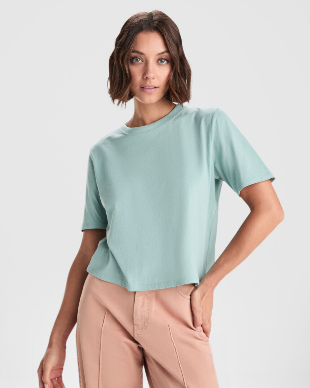 Mujer con camiseta verde menta y pantalón beige