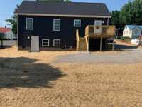 Back view with deck and walk-in storage underneath half of the home