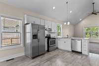 The kitchen features stainless appliance and bright white cabinetry