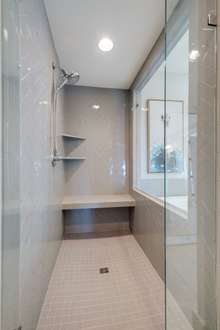 Luxurious oversized walk-in tiled shower in the primary suite, overlooking the garden tub, with custom frameless glass door