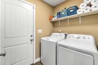 Laundry room with shelving that opens to the garage.