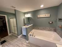 Main bathroom has farm style tile flooring & two separate vanities. Soak your cares away in this deep garden tub.