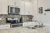 Gorgeous granite counter tops and tiled back splash. Plenty of cabinetry too! Classic white cabinets keep it light and bright.  