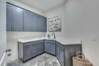 The laundry room has quartz counter tops, and new navy blue cabinetry for all your storage needs!  The floor is a stained concrete!