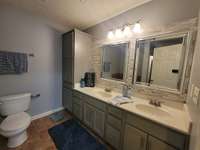 Primary bath with double vanities, tile flooring and custom back splash.