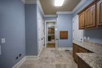 Large utility room with granite,custom cabinets,large storage closet and custom clothes chute from second floor.