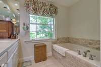 Neutral color stone tile surrounds this deep soaking tub.