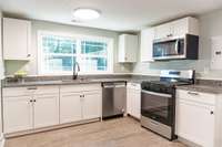 Kitchen has granite countertops, picture window above sink and stainless steel appliances including gas range. 