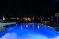 Nighttime view.  Water feature on rock wall of pool, 2 gas firepit/tables and torches for entertaining. The possibilities are endless.  Gas available for hook up if outdoor kitchen would be the next step for new homeowners.