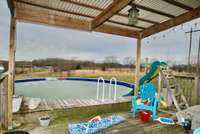 Above ground swimming pool with covered deck in the back of the house