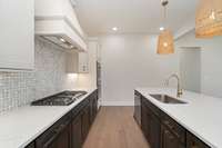 Just look at this kitchen! Gas cook top, tiled backsplash, quartz counters, custom cabinets, Designer lighting, double ovens, microwave, dishwasher, large pantry, wood hood, large island.