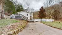 Parking area for 7431 River Road Pike.  Pool house overlooks fenced In-ground pool.