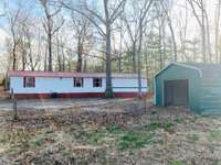 You have a mobile home with 3 BR, 2 BA, carport, shed with storm shelter, barn, pond, one bedroom cabin (gutted), and 5.5 acres all fenced in.