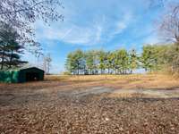 View from front of Trailer. The carport is large! There is a fenced area in front and pine trees that line the front of the property!!