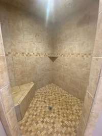 The walk in tile shower is large and has a bench, light and room to relax