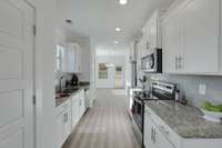 This convenient galley-style kitchen keeps essentials within reach.  The home listed is under construction.  This photo is of a similar home and floor plan.  Selections,  such as colors of paint, flooring, granite and cabinetry, will vary.