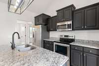 Fresh light fixtures help highlight the smooth countertops and double bowl kitchen sink