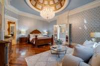 No detail was left undone in the design of this space. The cathedral-inspired ceiling and chandelier showcase the beautiful and spacious primary bedroom.