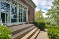 The main guest house entrance has expansive glass doors and is surrounded by rolling lawns and towering trees.