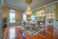 Seen here virtually staged, the formal dining room showcases the ornate details of custom millwork and gold accents with a crystal chandelier.