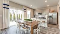 The spacious kitchen comes fully equipped with quartz countertops and stainless-steel appliances, while the dining room is incorporated into the open-concept space. *Photo of decorated model home