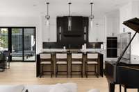 Kitchen features a beautiful stucco range hood and Restoration Hardware lighting over the main island