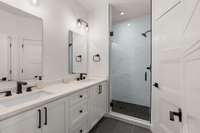 Full bathroom with double vanity and walk-in shower.