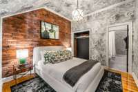 This ensuite guest room is dreamy with walls lined in puffy white clouds and features original brick walls and a marble-lined ensuite bath.