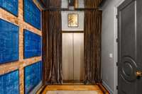 The private elevator with its heavy velvet drapery opens up into the luxe penthouse. The floor to ceiling panels are controlled by a remote adding to the 1920's hideaway feel when closed.