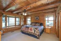 The primary bedroom has wonderful views on two sides. the wall of windows adds to the natural light seldom seen in log homes. There is literally a horse outside the window!