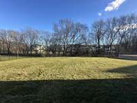 View of private back yard with mature tree row from the rear covered porch.  Back yard can accommodate a Pool.  Built By: Insignia Homes    photo taken: 2/23/24. *this home is under construction