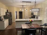 View from den into kitchen.  You can be in the kitchen and still watch the tv in the den and be a part of the party.  Note the updated lighting.