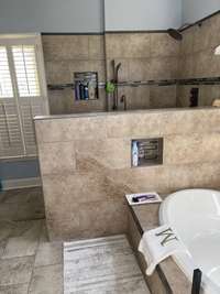 Oval soaking tub. Tile floor. Inserts in tile walls for holding shampoos, soap, etc.  Windows look out on the pation and backyard.