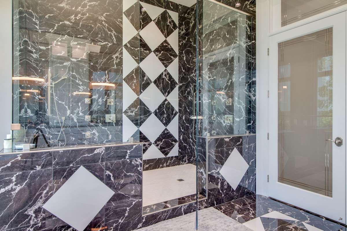 The marble tile and glass shower is a showpiece itself.