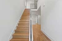 Welcoming foyer with gleaming white oak flooring, even on the steps.  Iron railing adds a modern twist.