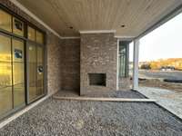 Slider doors open onto Covered Outdoor Living area with Fireplace and dining/grilling station *this home is under construction Photo taken 2/5//24