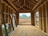 Large Primary Suite featuring a vaulted ceiling with beam ceiling detail and floor to ceiling windows *this home is under construction Photo taken: 1/8/24