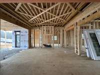 Grand Great Room featuring a 12'ceiling with applied trim detail, wood-burning fireplace large slider doors with transom  *this home is under construction Photo taken: 1/8/24