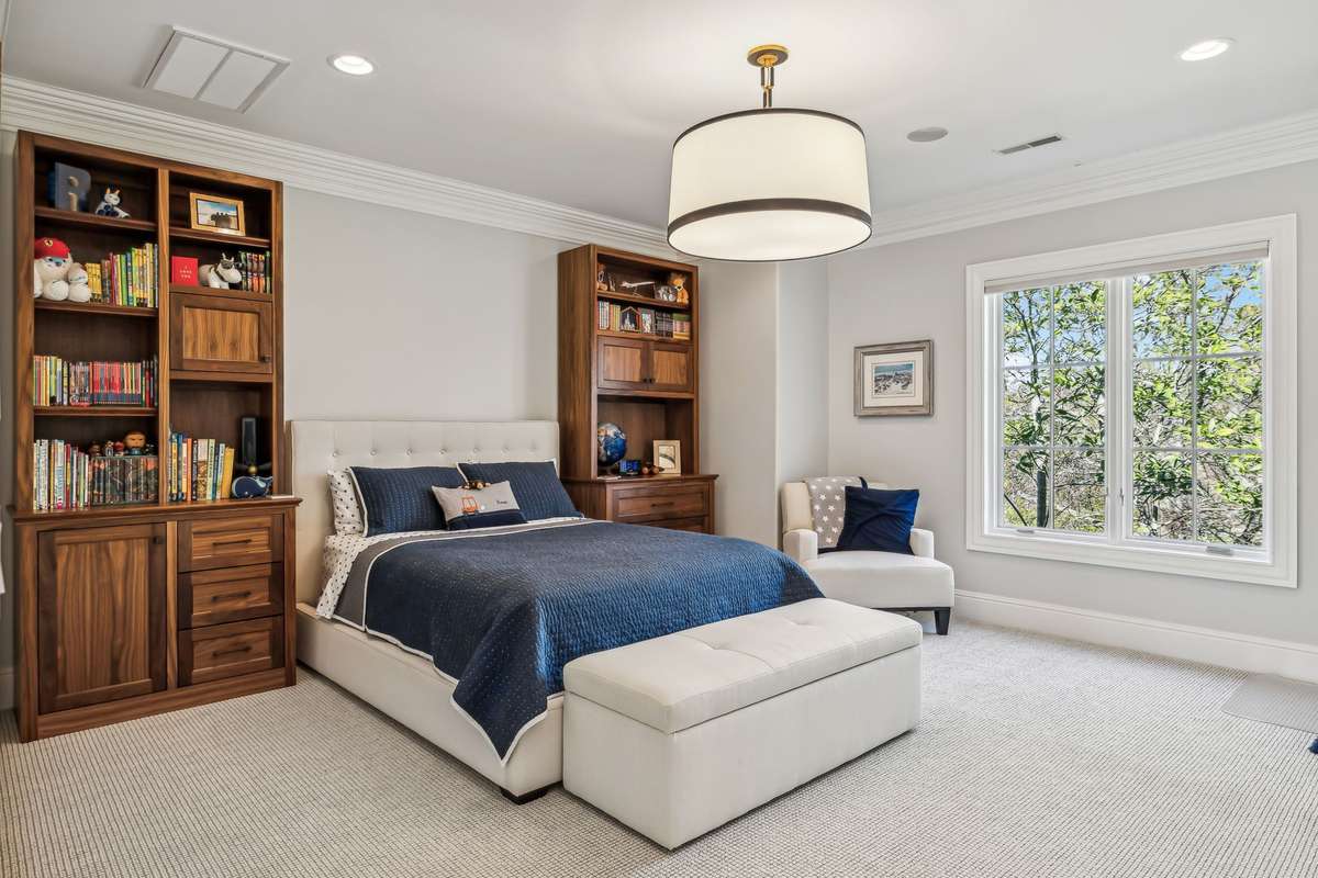 Bedroom #3 features Hunter Douglas automated blackout window treatments for ultimate privacy, plush Berber carpeting layered over a soft memory foam pad, and a statement light fixture with a large, shaded design that adds an ambient glow.