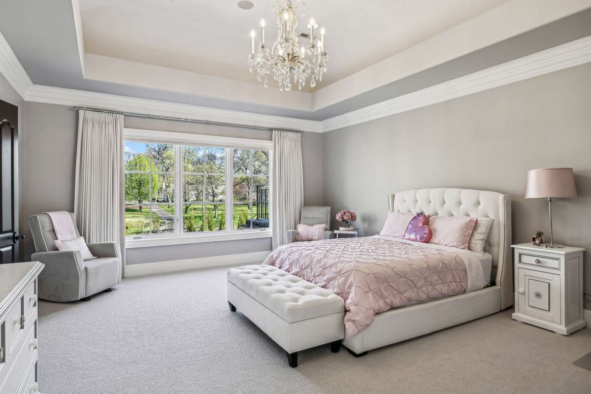Bedroom #4 exudes elegance with its tray ceiling crowned by a crystal-accented chandelier. The room features plush Berber carpeting layered over a memory foam pad and windows outfitted with Hunter Douglas automated blackout shades.